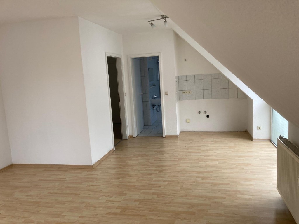 Helles Appartement in der Amberger Straße: Wohnraum mit Laminat, vorbereiteter Küchenzeile, Blick ins Bad und Zugang zum Balkon